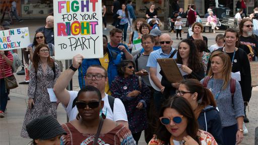 People marching with a sign saying "Fight for Your Right to Party"
